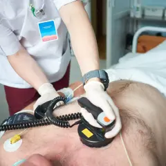 Ratownik medyczny wykonuje kardiowersję pacjentowi w szpitalu, używając defibrylatora.