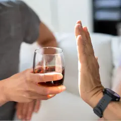 Dłoń odrzuca kieliszek z alkoholem.