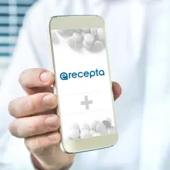 Dłoń trzyma smartfon z logo e-recepty i pigułkami.