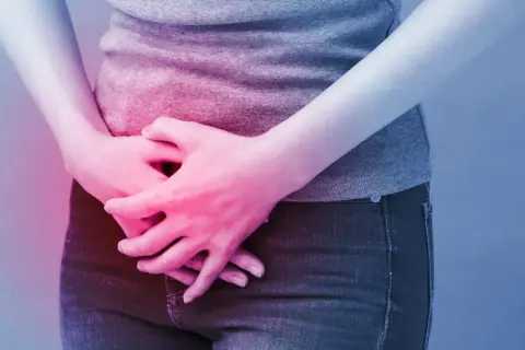 Osoba trzyma się za brzuch, odczuwając ból. Może to być objaw problemów z pęcherzem, które łagodzi ditropan.