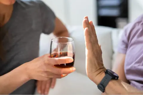 Dłoń odrzuca kieliszek z alkoholem.