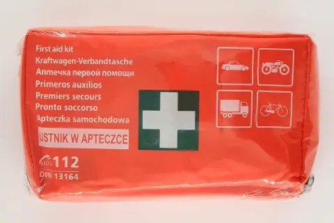 Pomarańczowa apteczka samochodowa z białym krzyżem i ikonami pojazdów.