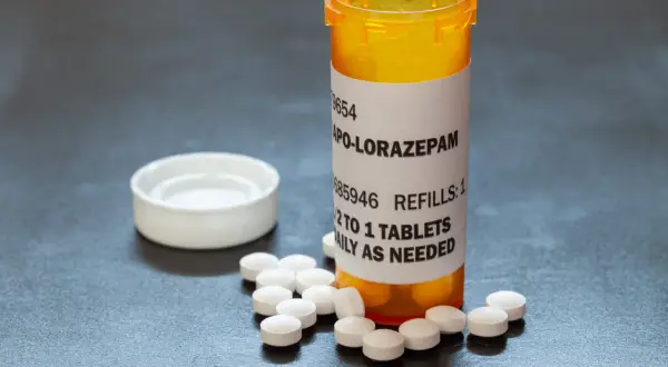 Butelka z lekami APO-LORAZepam, obok rozsypane tabletki. Dawkowanie: 1/2 do 1 tabletki dziennie w razie potrzeby.