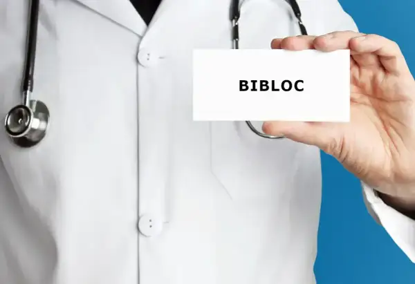 Lekarz w białym kitlu trzyma kartkę z napisem "BIBLOC". To nazwa handlowa leku bisoprolol, stosowanego w leczeniu chorób serca.