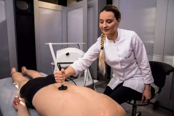 Fizjoterapeutka wykonuje kriolezję stawu biodrowego u pacjenta leżącego na kozetce.